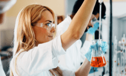 Female scientist looking at beaker in science lab.