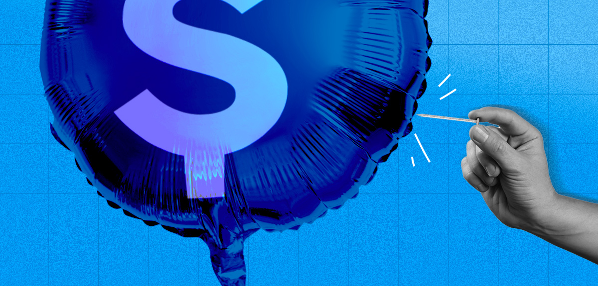 A hand popping a balloon with a money sign on it